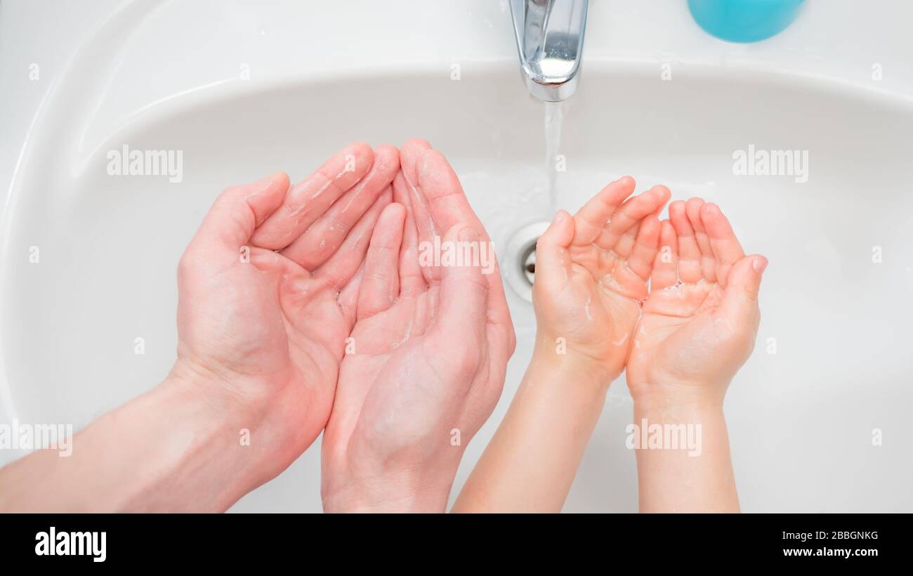 Arrière-plan des mains lavantes. Mains d'un enfant et d'un adulte près du lavabo. Protection contre la maladie du coronavirus COVID-19. Concept de lavage des mains. Mains du père Banque D'Images