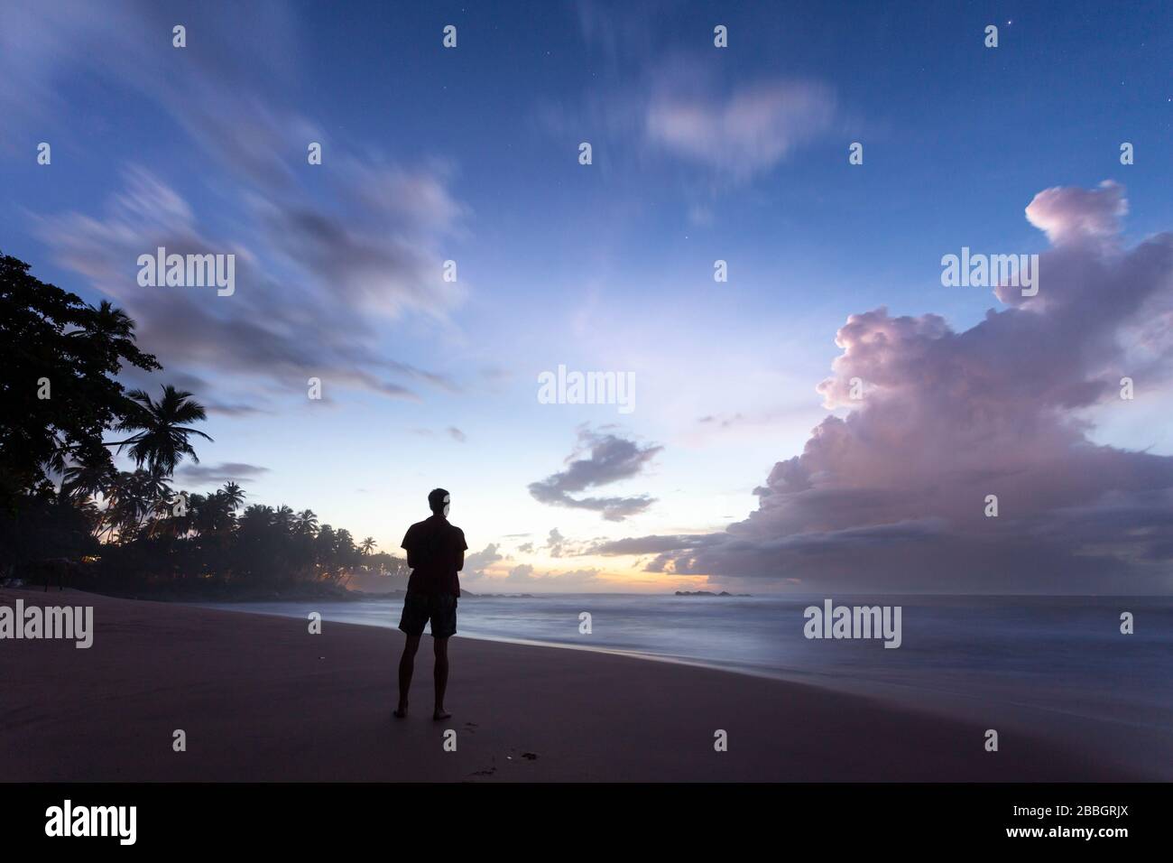 Homme se tenant sur la plage de Goyambokka juste avant le lever du soleil, Sri Lanka Banque D'Images