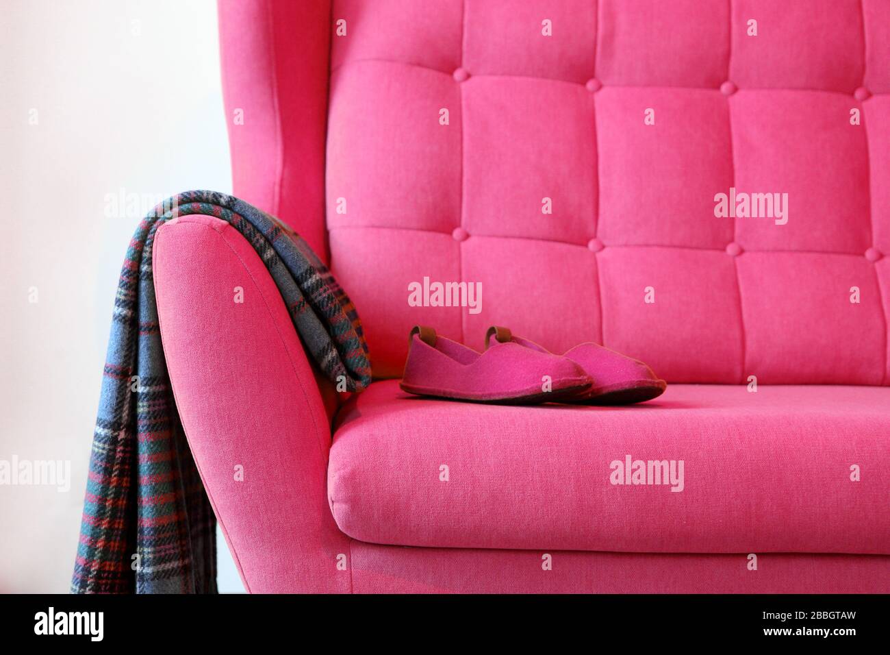 Pantoufles roses et couverture sur un autocar rose. Encore des détails de la vie dans la maison intérieure du salon. Intérieur confortable, concept de confort à la maison, sans sexe Banque D'Images