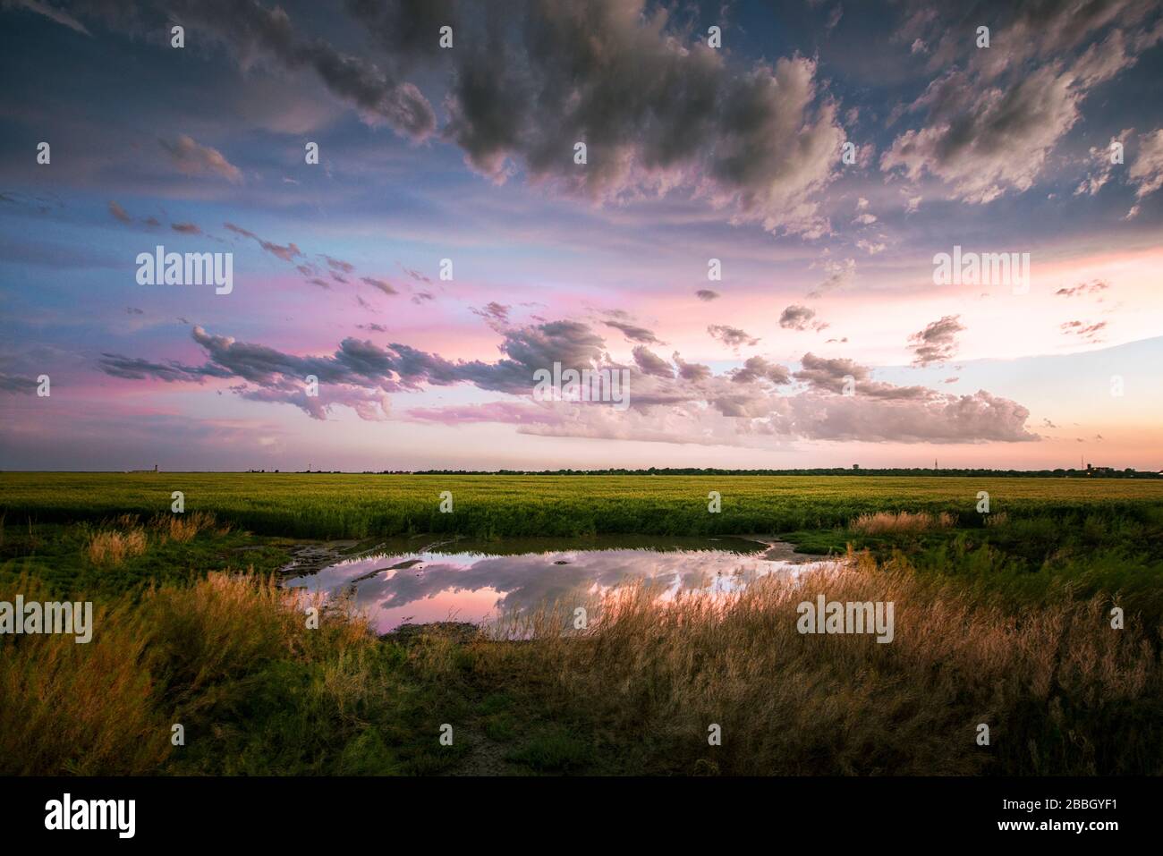 Coucher de soleil sur un étang avec une réflexion parfaite comme une tempête passe près de Dodge City Kansas Etats-Unis Banque D'Images