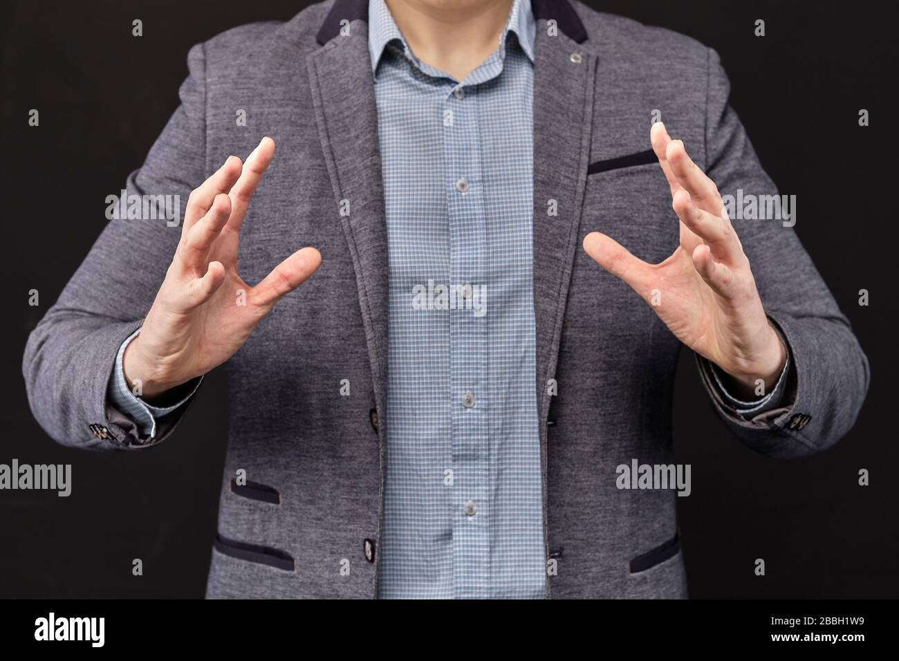 L'homme dans une veste montre avec ses mains un objet abstrait. Gros plan. Banque D'Images