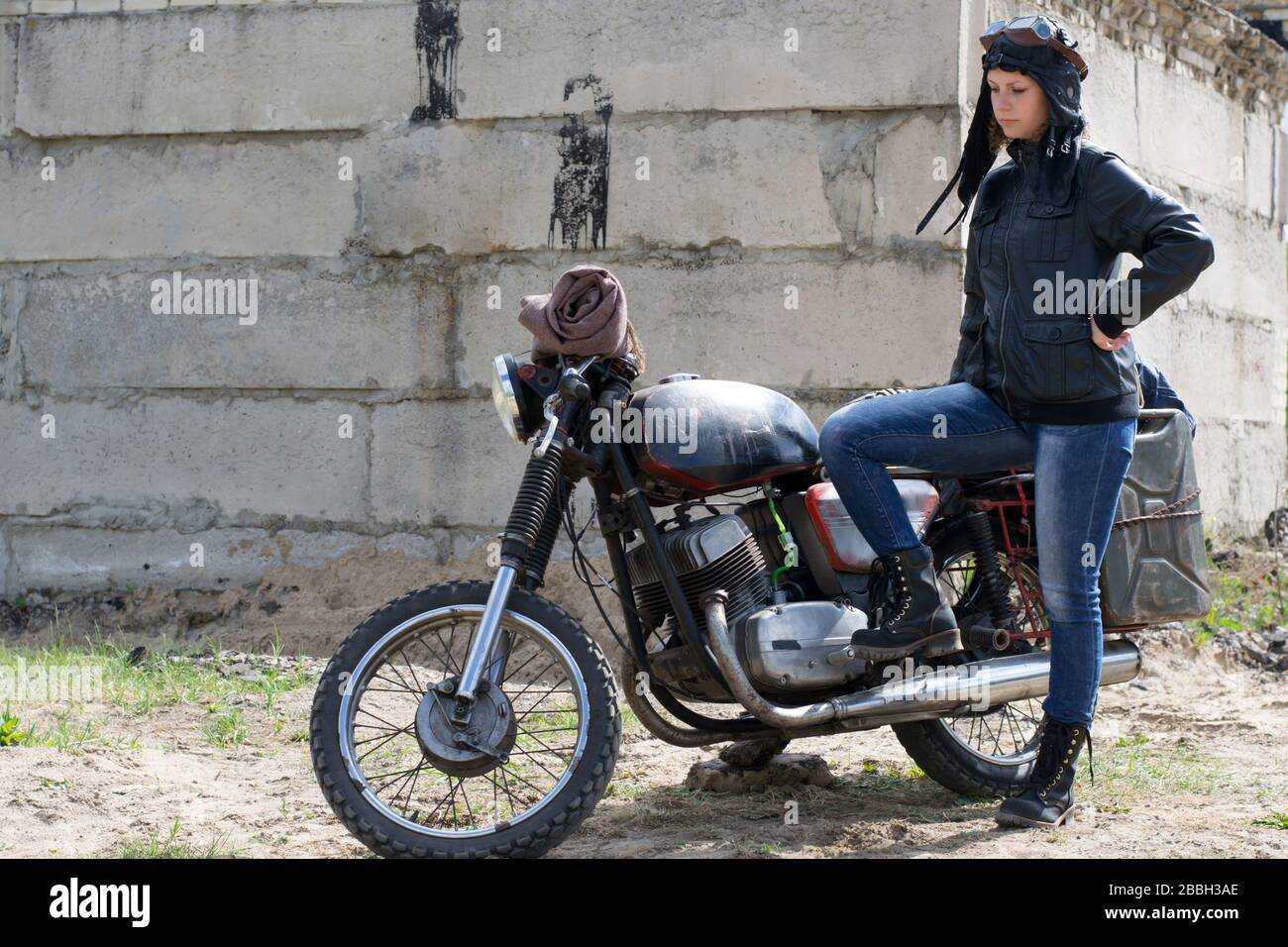 Une femme post apocalyptique près de la moto près de la construction détruite Banque D'Images