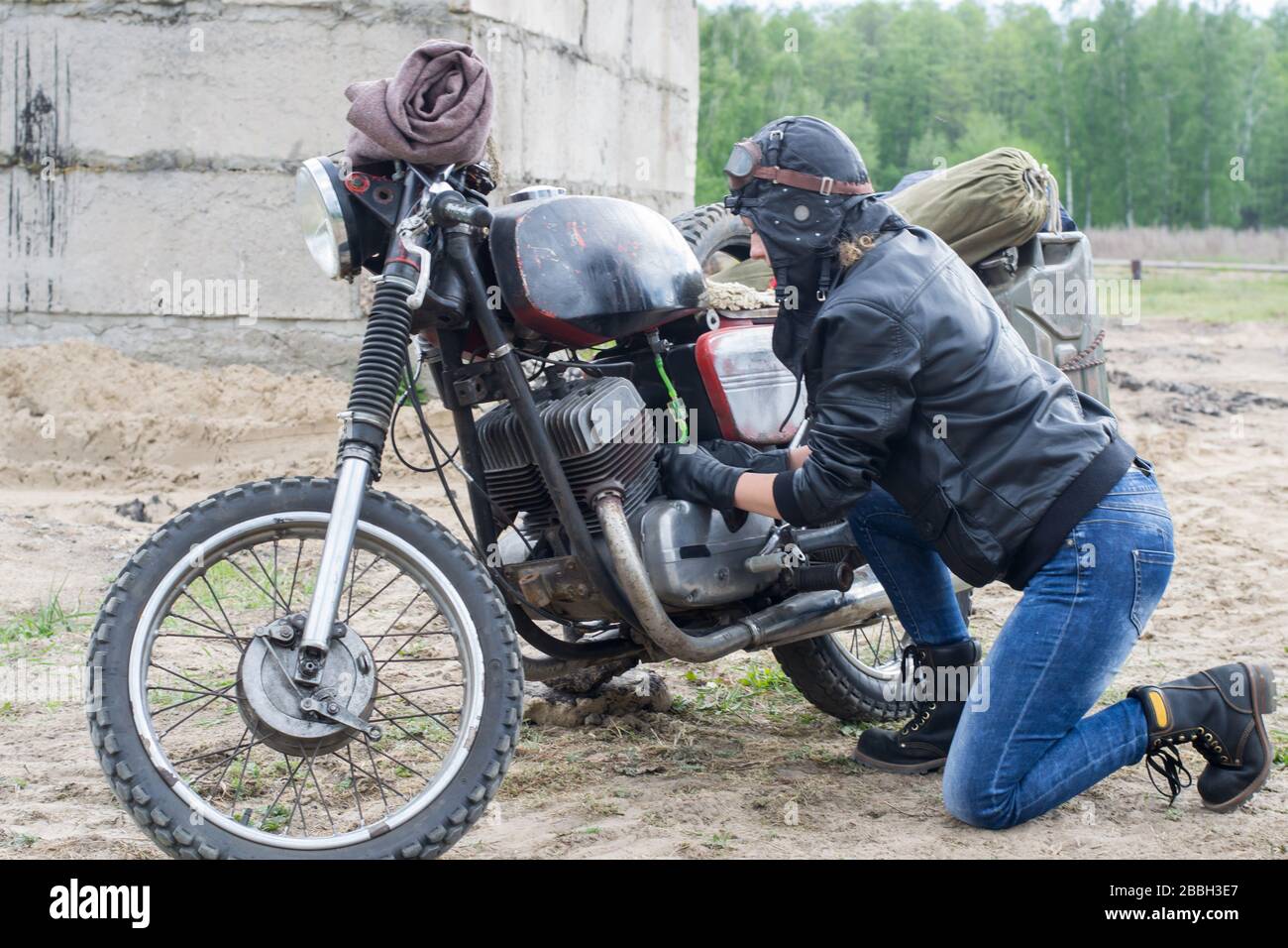 Une femme post apocalyptique près de la moto près de la construction détruite Banque D'Images