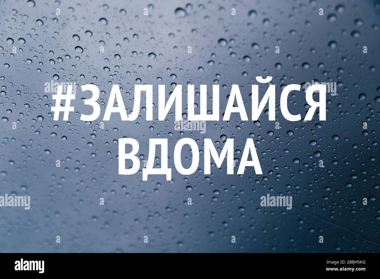 Rester à la maison dans la campagne des médias sociaux de langue ukrainienne pour la prévention du coronavirus. Restez à la maison concept de sécurité. Gros plan des gouttes de pluie sur la fenêtre Banque D'Images
