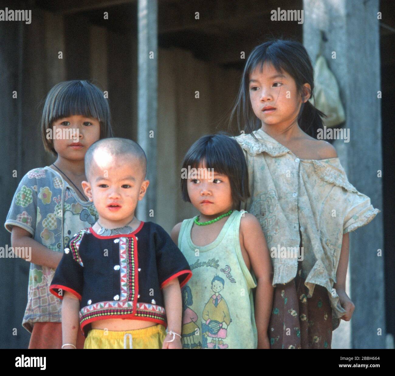 Quatre jeunes enfants lao dans un village au bord du Mékong, près de Luang Prabang, au Laos. Ils ont une gamme d'expressions allant de curieux à timide. Le plus jeune a une chemise traditionnelle et un collier de pièces de monnaie. La ville de Luang Prabang est classée au patrimoine mondial de l'UNESCO. Banque D'Images