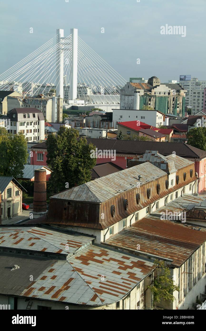 Paysage urbain avec constructions anciennes et nouvelles à Bucarest, Roumanie. Nouveau pont suspendu par câble dominant la vue. Banque D'Images