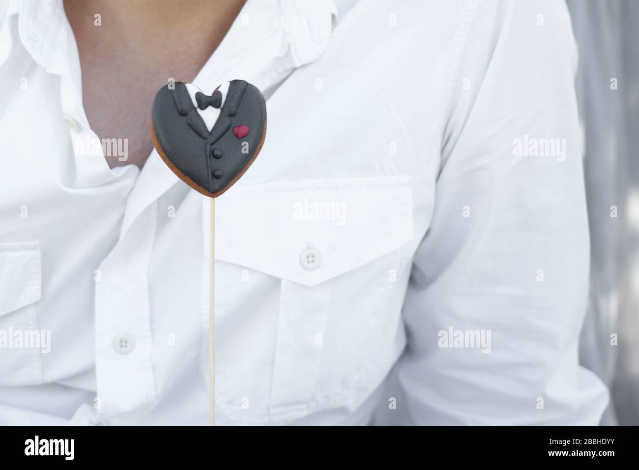 Cookies sous forme de vêtements de groom sur des bâtons sur l'homme dans un fond de chemise blanche Banque D'Images