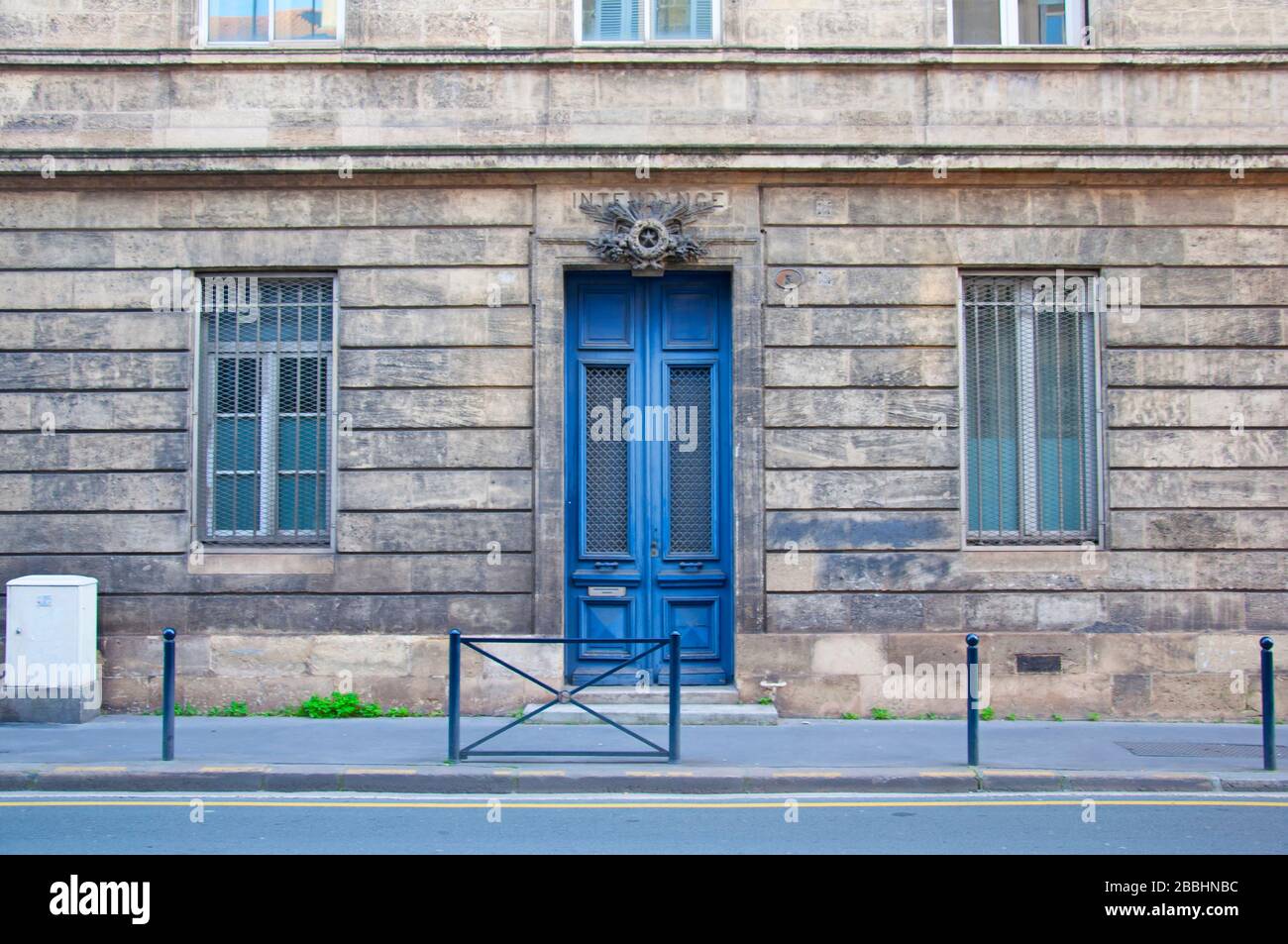 Porte en bois bleu haut avec deux fenêtres étroites sur la façade grise du bâtiment, Bordeaux, France Banque D'Images