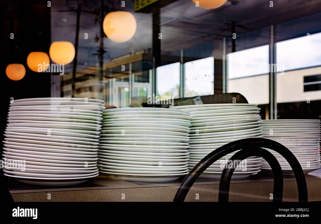Les plaques vides sont empilées sur un comptoir dans une Waffle House qui a fermé en raison de COVID-19, le 29 mars 2020, à Mobile, Alabama. Banque D'Images