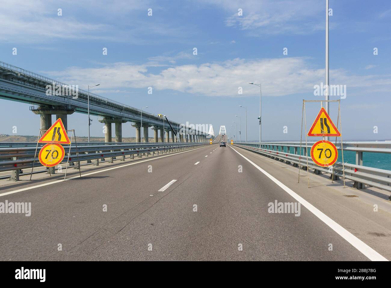 Panneaux de limitation de vitesse jaune de la voiture et rétrécissement de la route en raison de réparations. Pont de Crimée traversant le détroit de Kerch Banque D'Images
