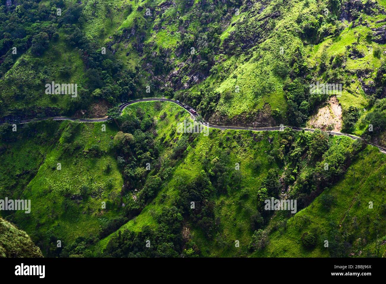 Route de montagne incurvée avec voitures et bus depuis la vue aérienne. Herbe de couleur verte vive sur les montagnes rocheuses. Route en serpentine venteuse près d'Ella, Sri Lanka Banque D'Images