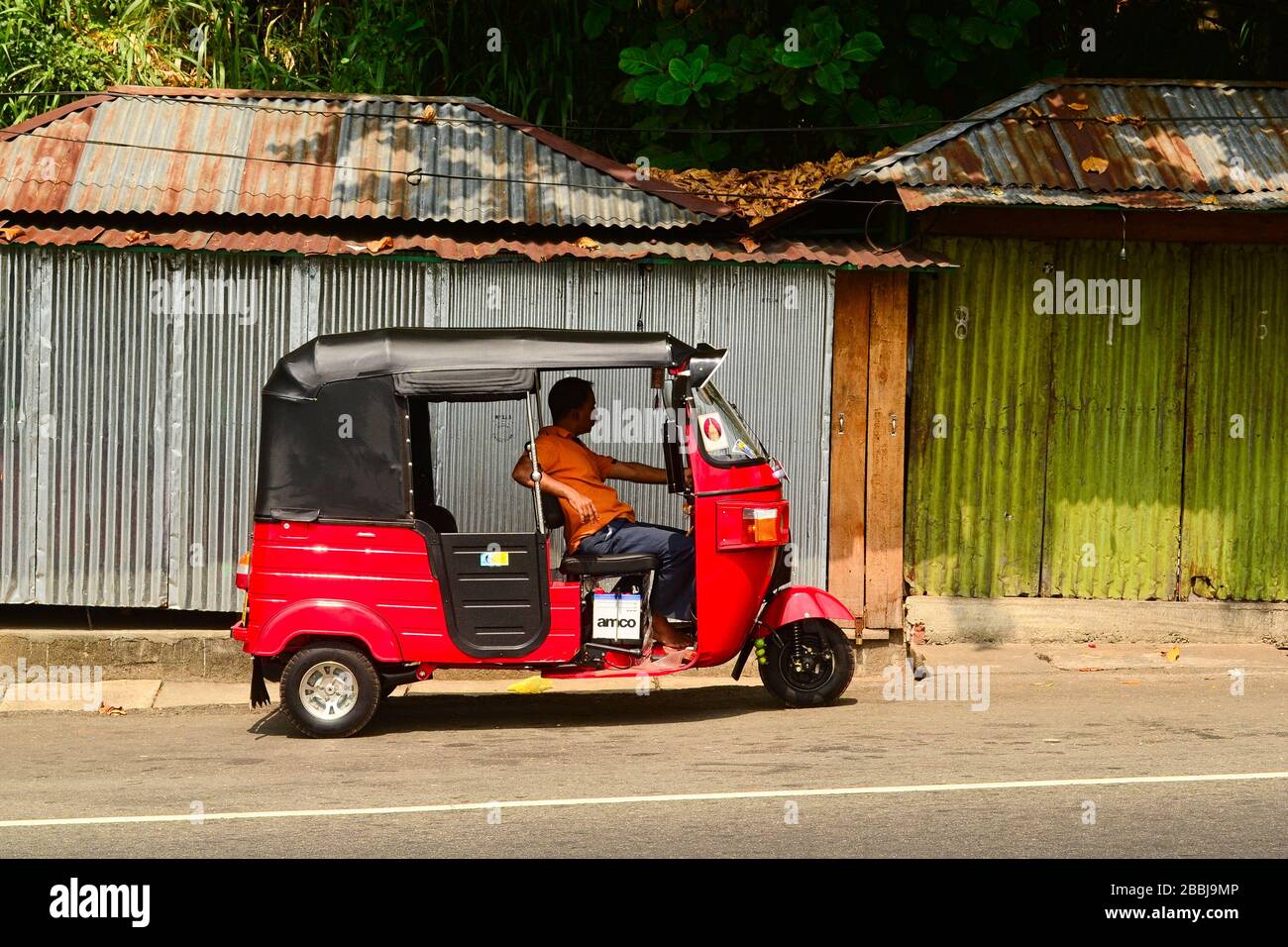 Kadogannawa, Sri Lanka - février 2014 : conducteur tuk tuk en attente de passagers dans son pousse-pousse rouge à trois roues Banque D'Images