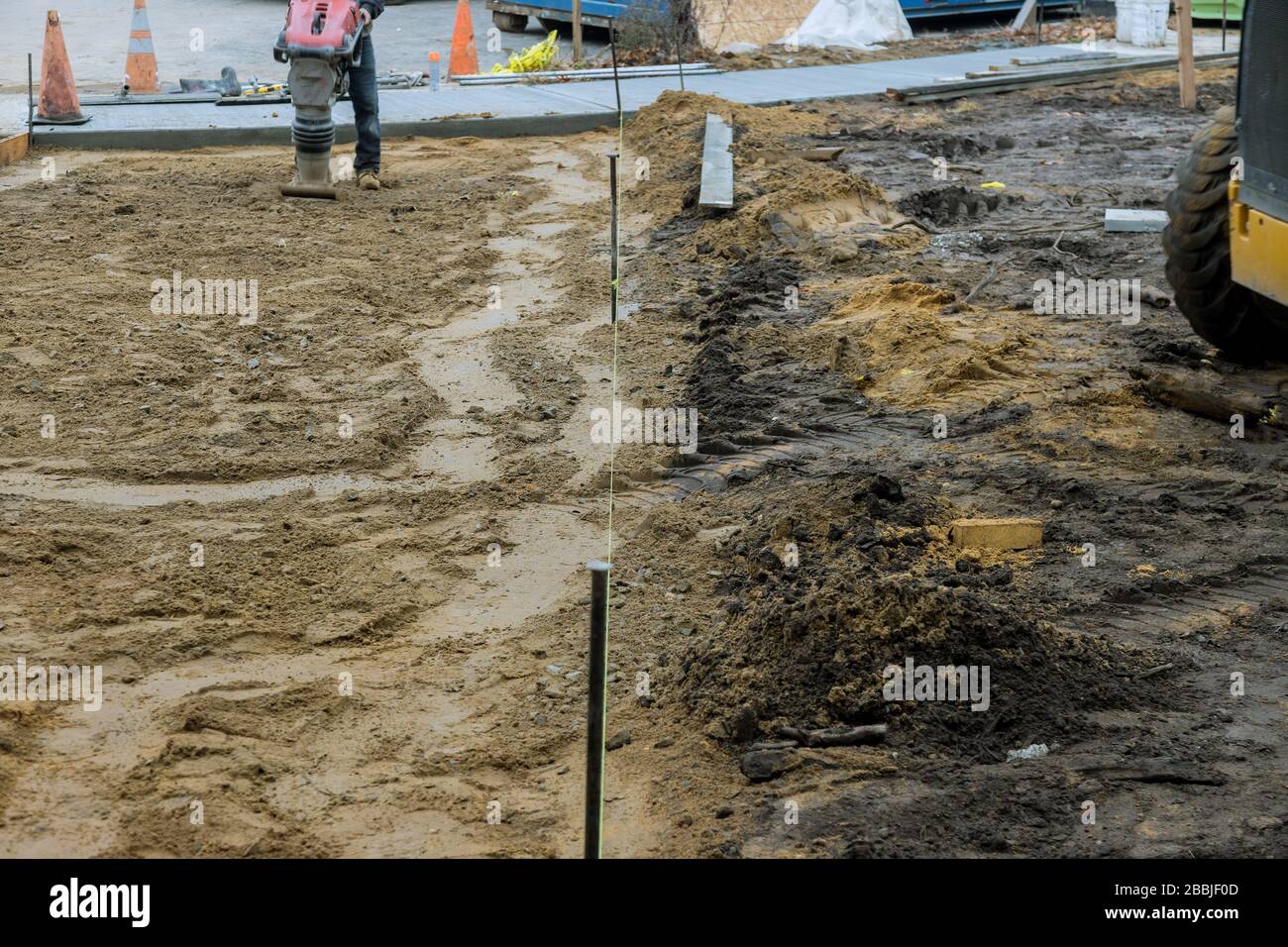 Travaux de construction sur un pavé qui exploite un rammer de terre vibrant compactant le sol Banque D'Images