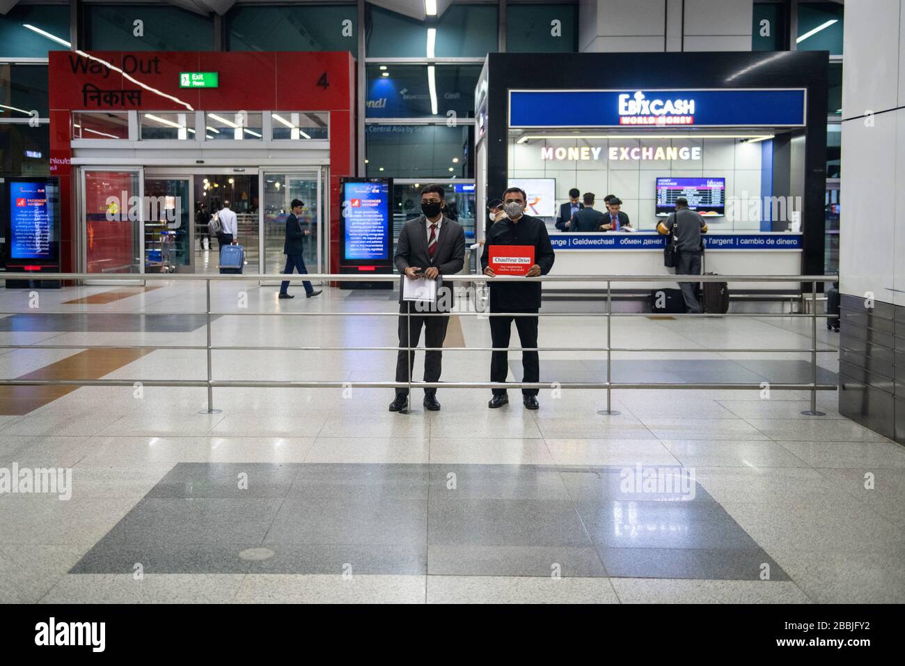 Les conducteurs portent des masques lorsqu'ils attendent les passagers arrivant dans un hall d'arrivée pratiquement vide à l'aéroport de Delhi, en Inde. Banque D'Images