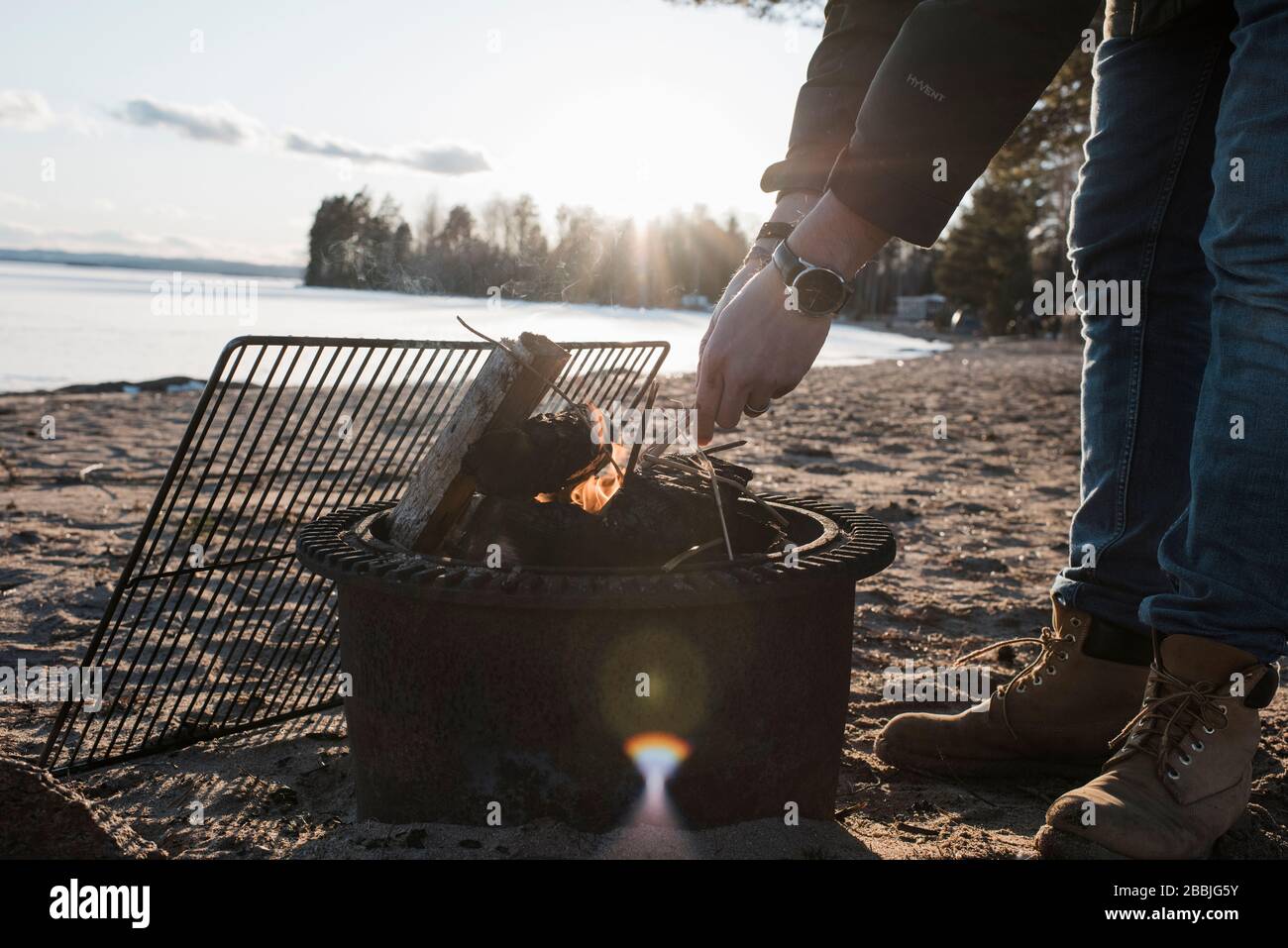 Mains d'homme éclairant un feu de joie dehors sur une plage en Suède Banque D'Images