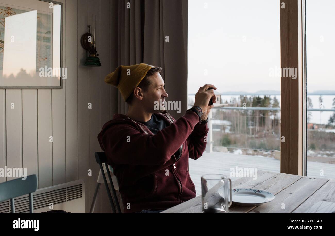 Homme prenant des photos de la vue depuis son balcon à la maison en Suède Banque D'Images
