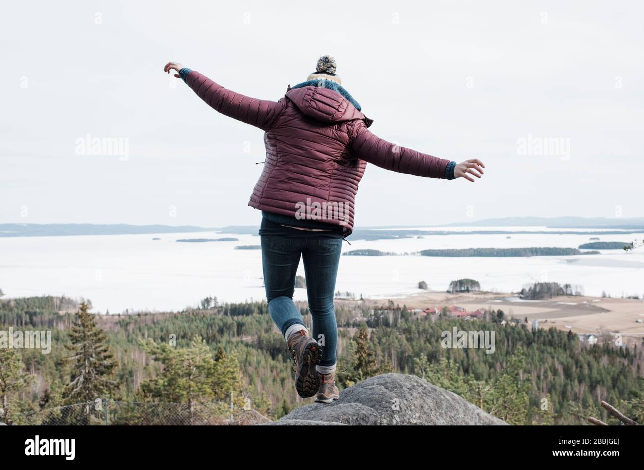 femme sautant d'un rocher tout en randonnée avec vue sur l'océan Banque D'Images
