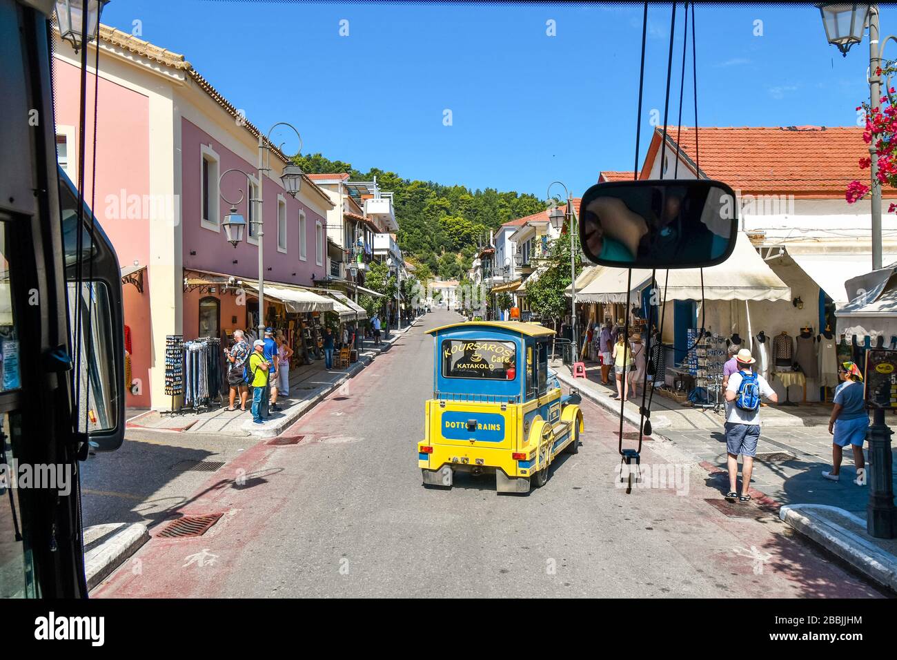 Un tour-bus suit un train touristique lorsqu'il traverse le petit village côtier de Katakoloon, en Grèce, site du port de croisière Olympia. Banque D'Images
