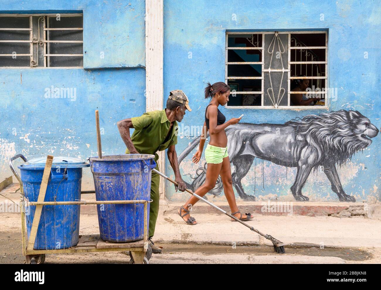 Streert Cleaner regarde des peintures murales de filles et d'art de rue à la Havane Vieja, Cuba Banque D'Images