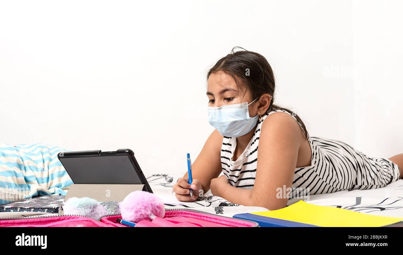 Jeune fille asiatique étudiant en ligne dans sa chambre portant un masque de protection du visage en raison de l'actuelle pandémie de virus corona - la santé et l'éducation con Banque D'Images