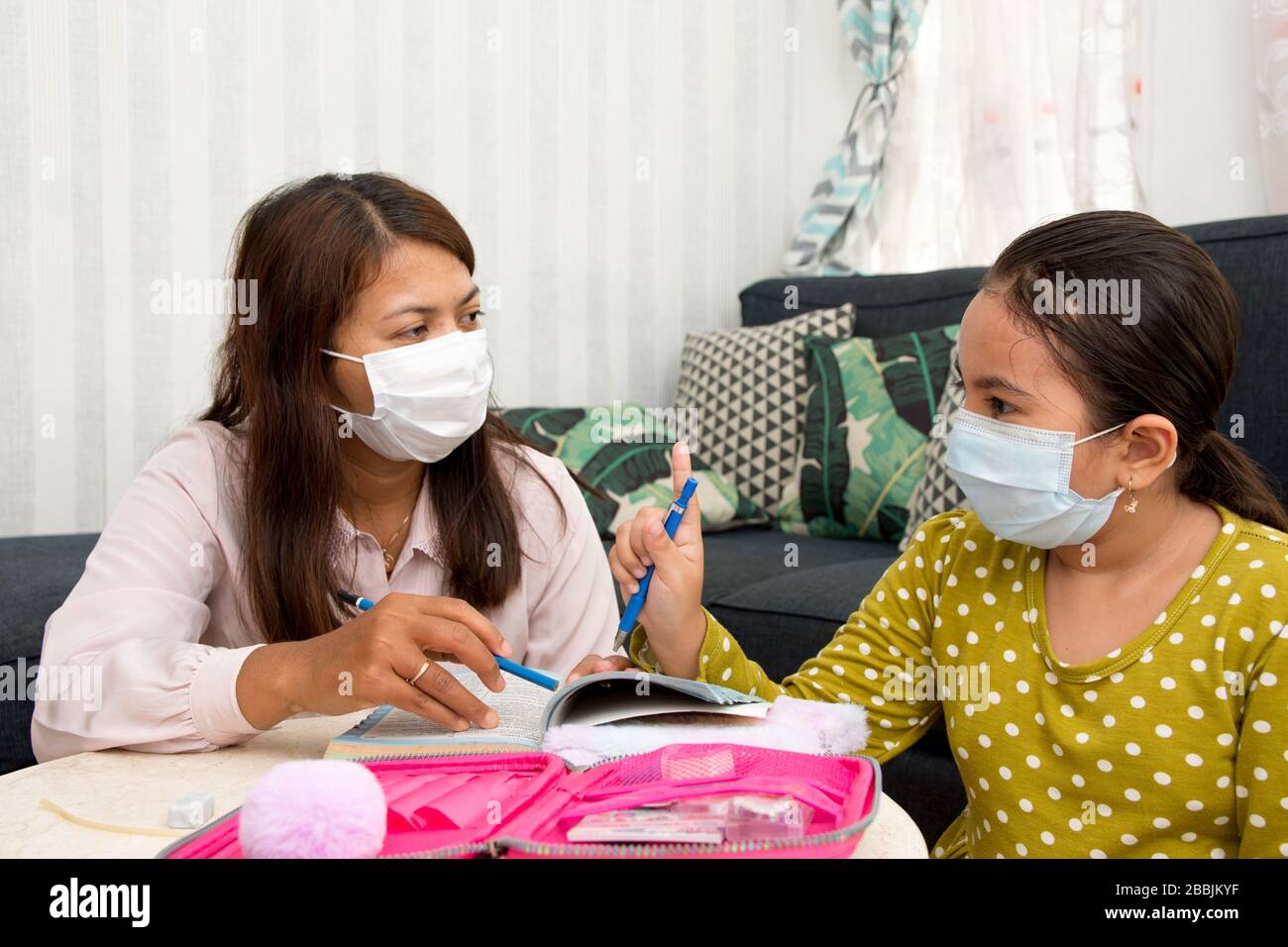 Accueil école concept image avec la mère et la fille étudier en portant des masques de visage en raison de la menace actuelle du virus corona - soins de santé actuels / Banque D'Images