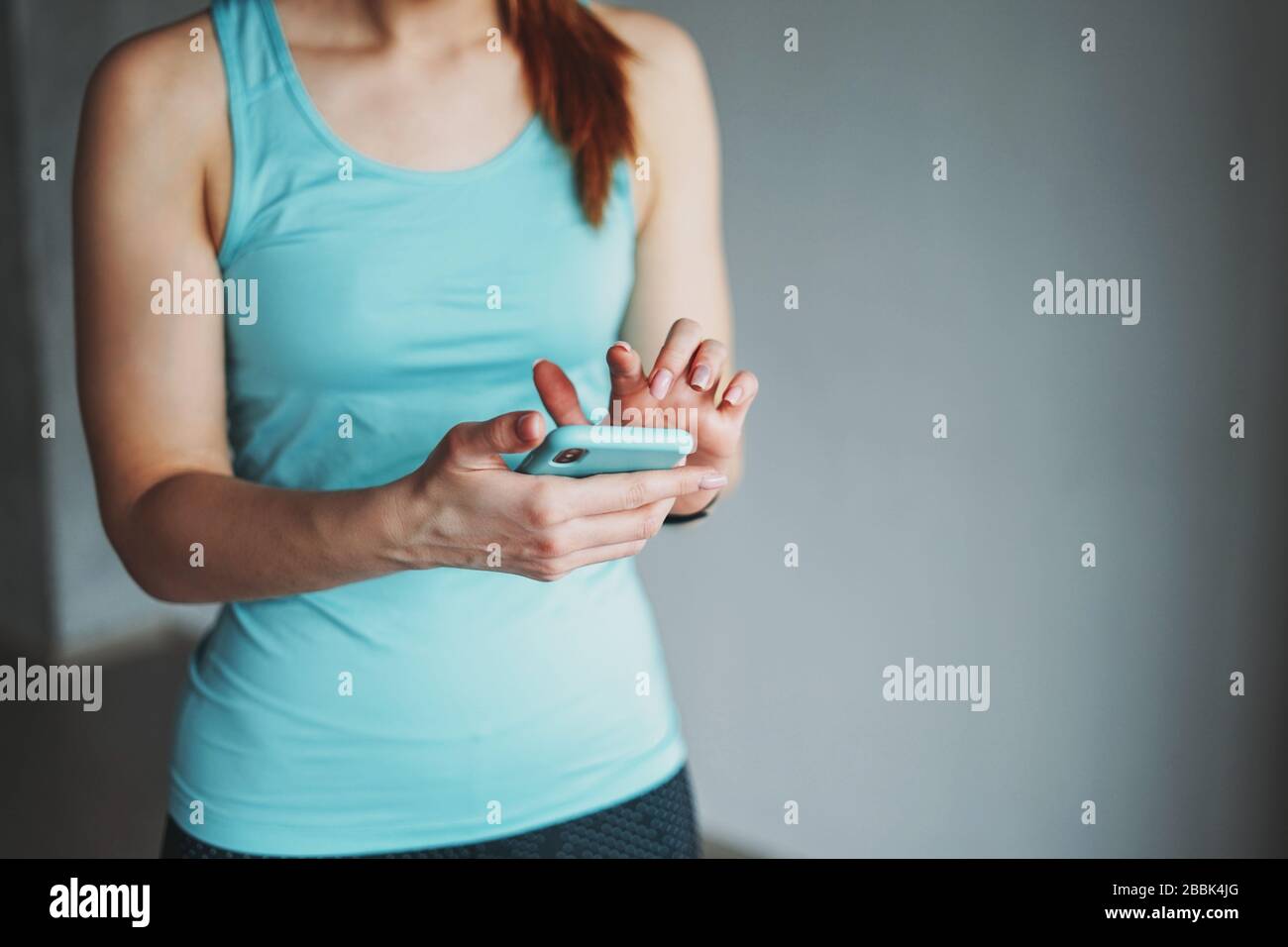 Tenue attrayante jeune femme bleu clair sport porter faire de l'entraînement avec mobile à l'atelier de classe d'entraînement Banque D'Images