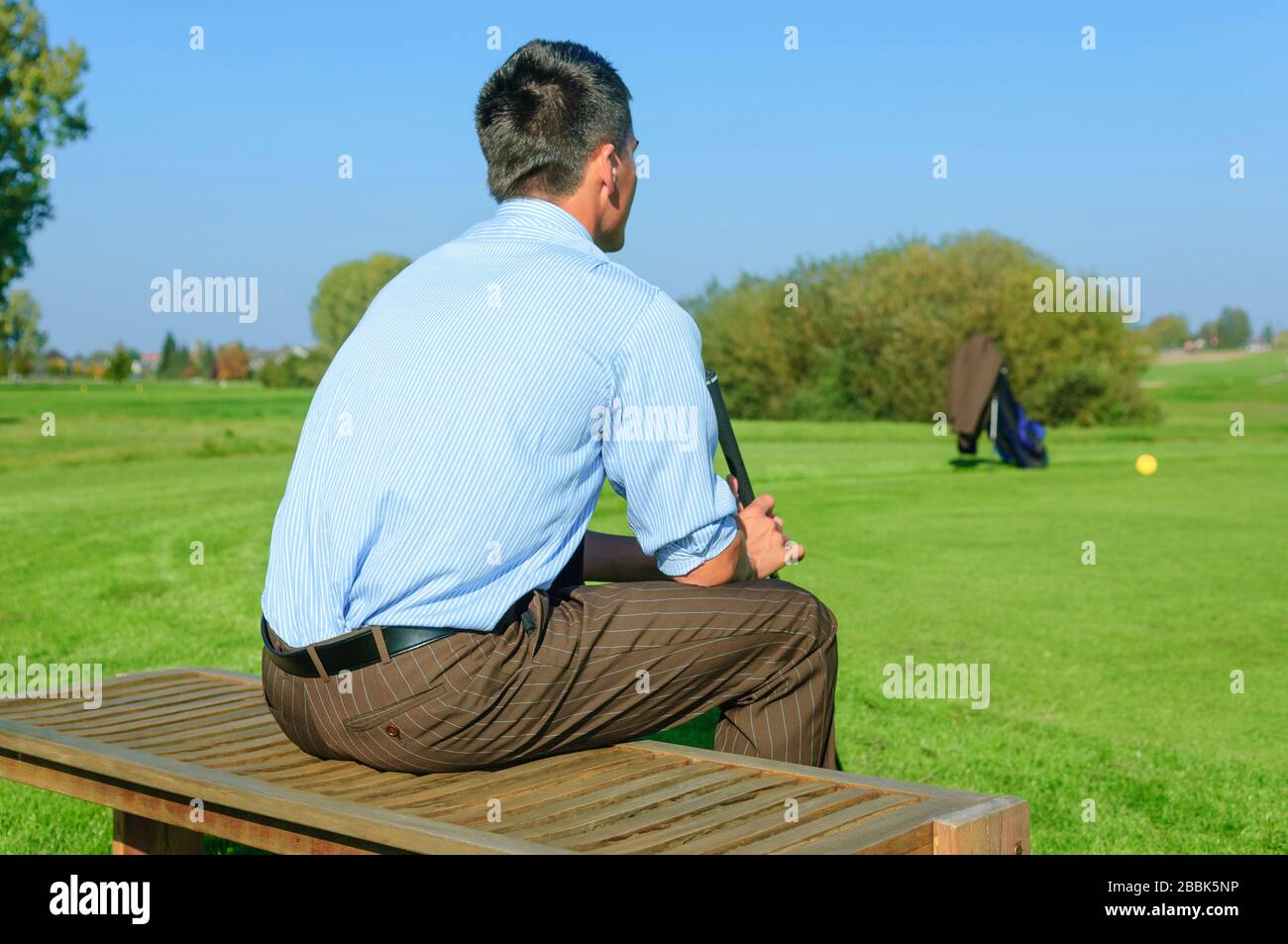 Homme en tenue d'affaires jouant au golf dans l'après-midi Banque D'Images