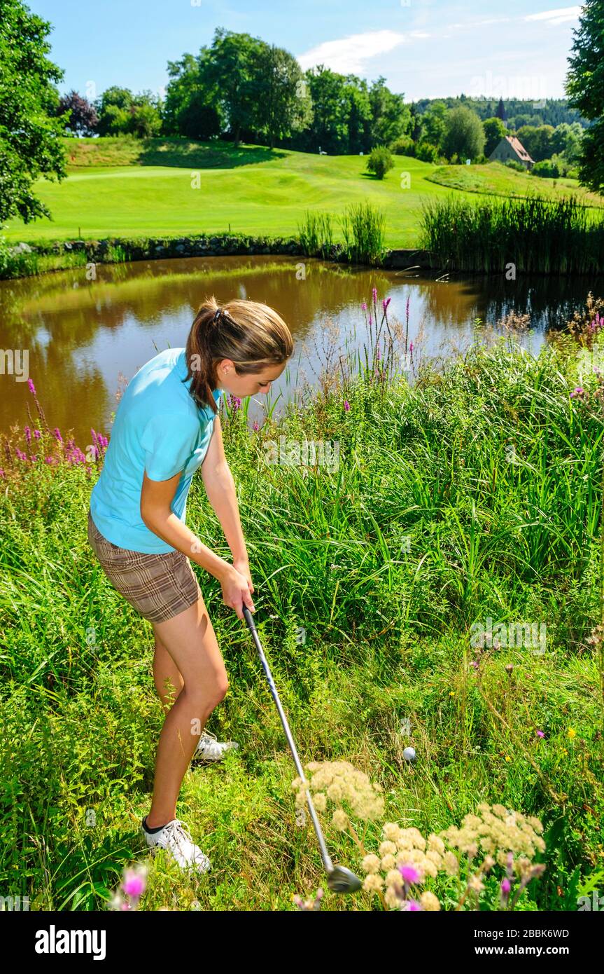Jeune joueur de golf féminin jouant au ballon dans rugueux Banque D'Images