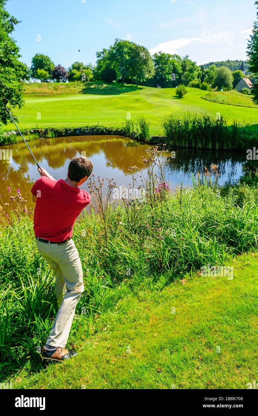 Jeune joueur de golf jouant au ballon dans rugueux Banque D'Images