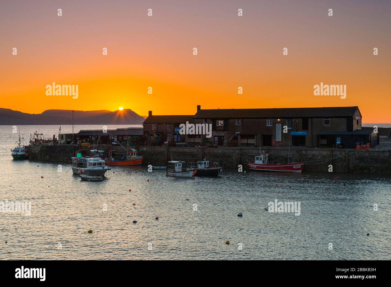 Lyme Regis, Dorset, Royaume-Uni. 1 avril 2020. Météo britannique. Le ciel clair brille en orange au-dessus du port de Cobb au lever du soleil à Lyme Regis à Dorset. Crédit photo : Graham Hunt/Alay Live News Banque D'Images
