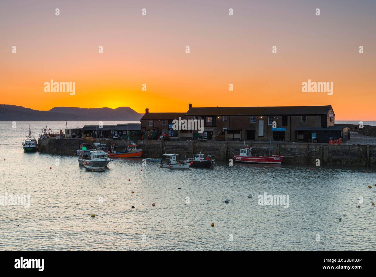 Lyme Regis, Dorset, Royaume-Uni. 1 avril 2020. Météo britannique. Le ciel clair brille en orange au-dessus du port de Cobb au lever du soleil à Lyme Regis à Dorset. Crédit photo : Graham Hunt/Alay Live News Banque D'Images