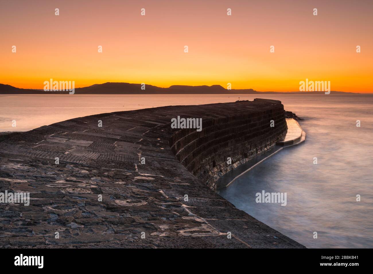 Lyme Regis, Dorset, Royaume-Uni. 1 avril 2020. Météo britannique. Le ciel clair brille en orange au-dessus du port de Cobb au lever du soleil à Lyme Regis à Dorset. Crédit photo : Graham Hunt/Alay Live News Banque D'Images