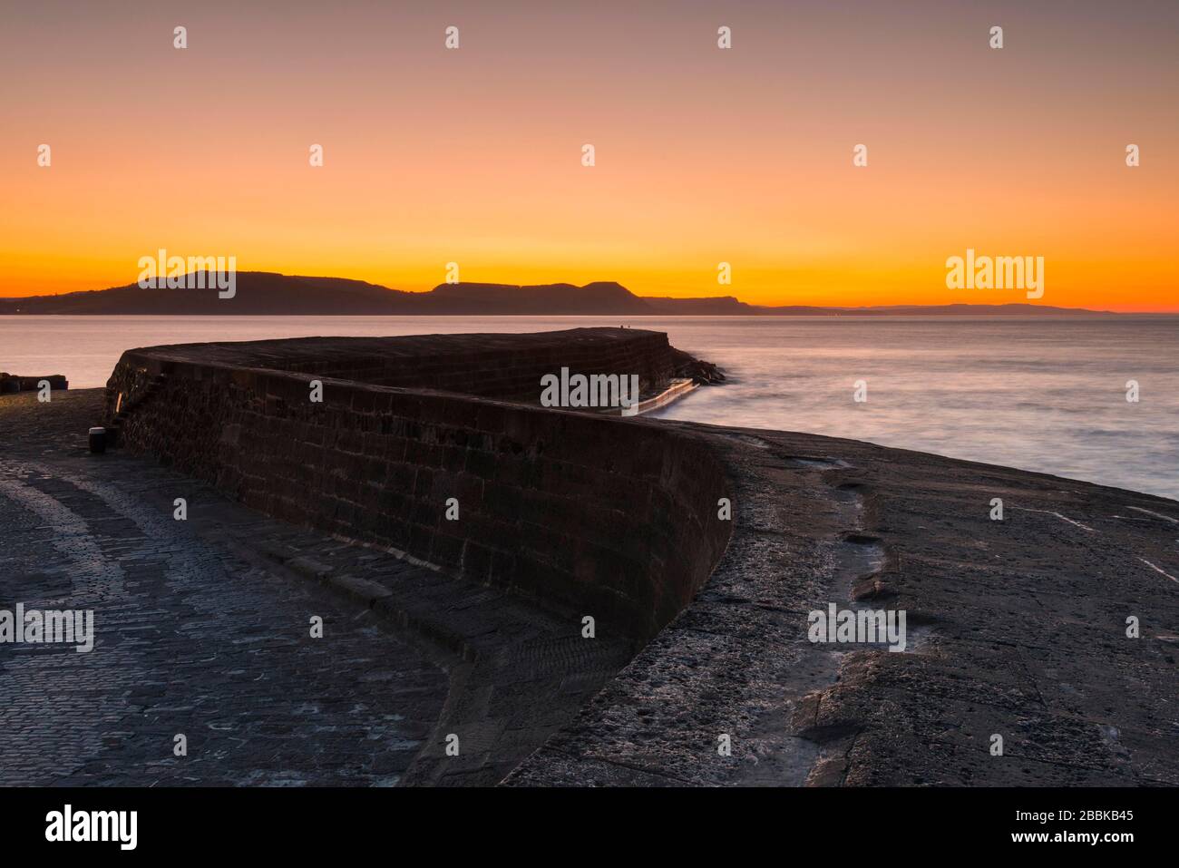 Lyme Regis, Dorset, Royaume-Uni. 1 avril 2020. Météo britannique. Le ciel clair brille en orange au-dessus du port de Cobb au lever du soleil à Lyme Regis à Dorset. Crédit photo : Graham Hunt/Alay Live News Banque D'Images