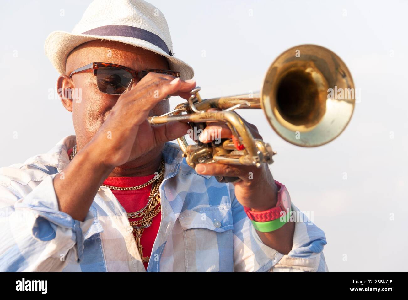 HAVANA, CUBA - 01 AVRIL 2017 : portrait du musicien de rue cubain noir avec chapeau et lunettes de soleil jouant à la trompette à l'extérieur Banque D'Images