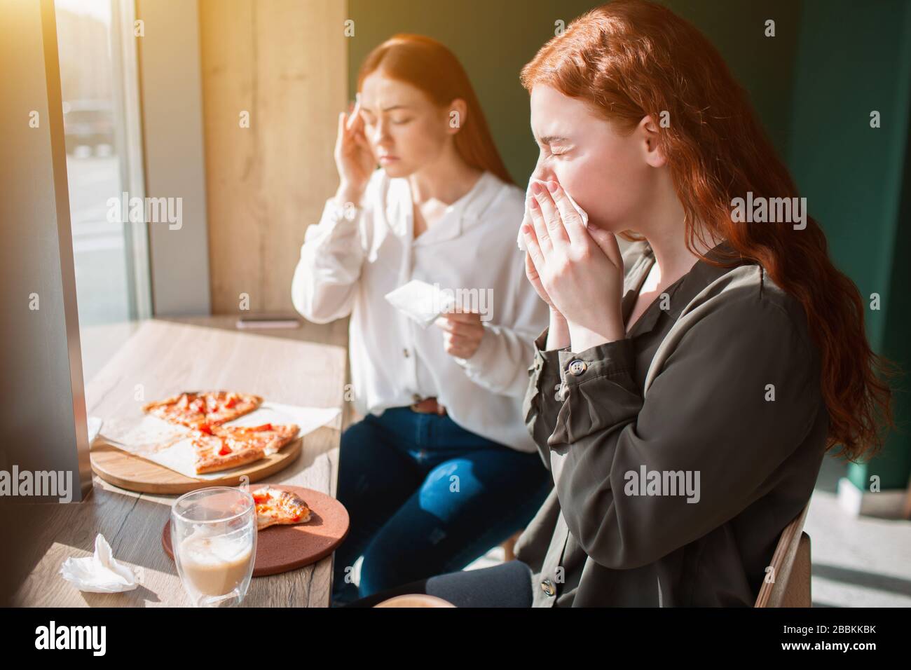 Le modèle féminin se trouve dans un café et souffle son nez. Une jeune femme ressent un mal de