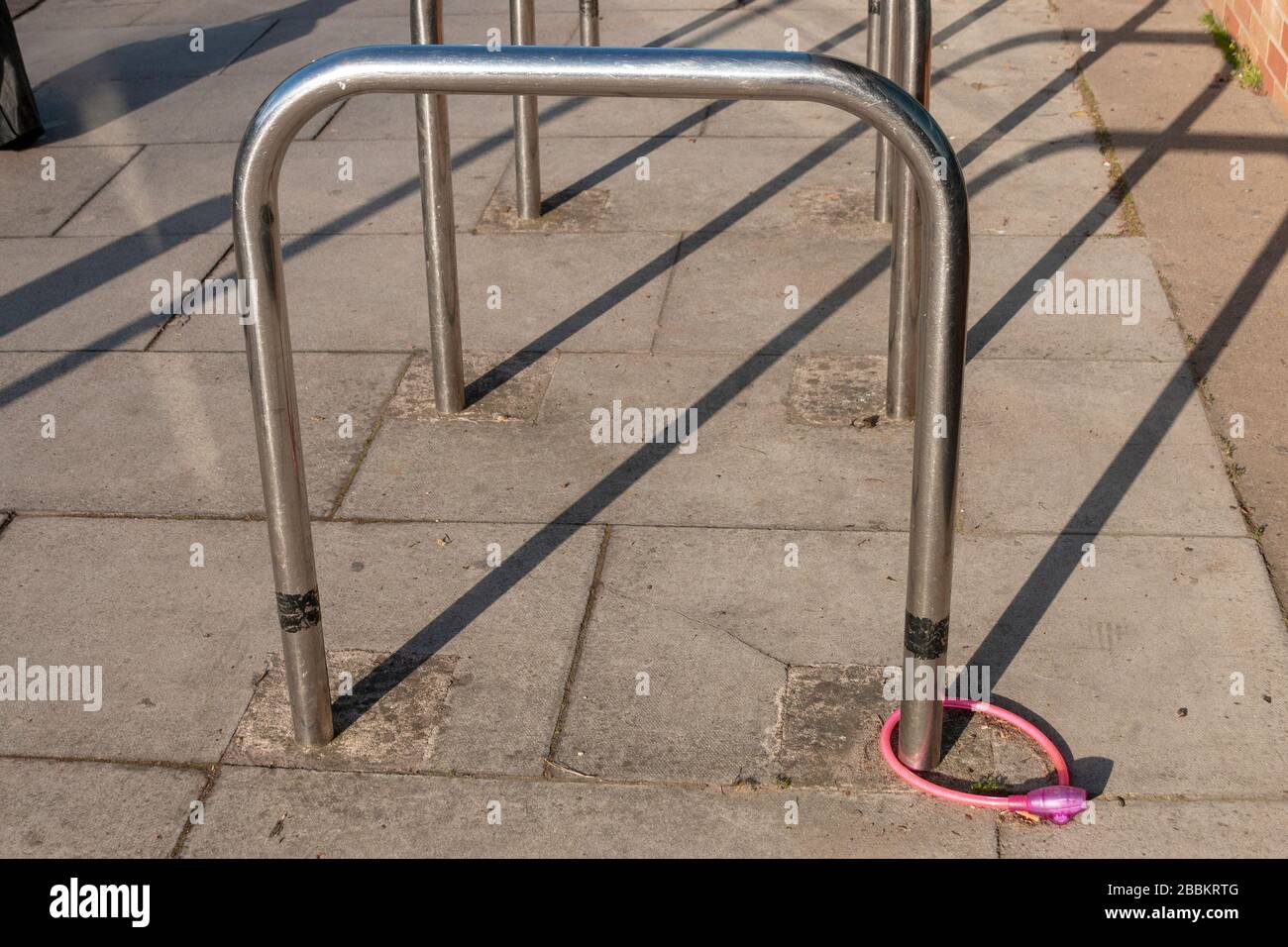 vue rapprochée d'un cadenas de vélo rose et d'une chaîne reliée à un poste de vélo en métal Banque D'Images