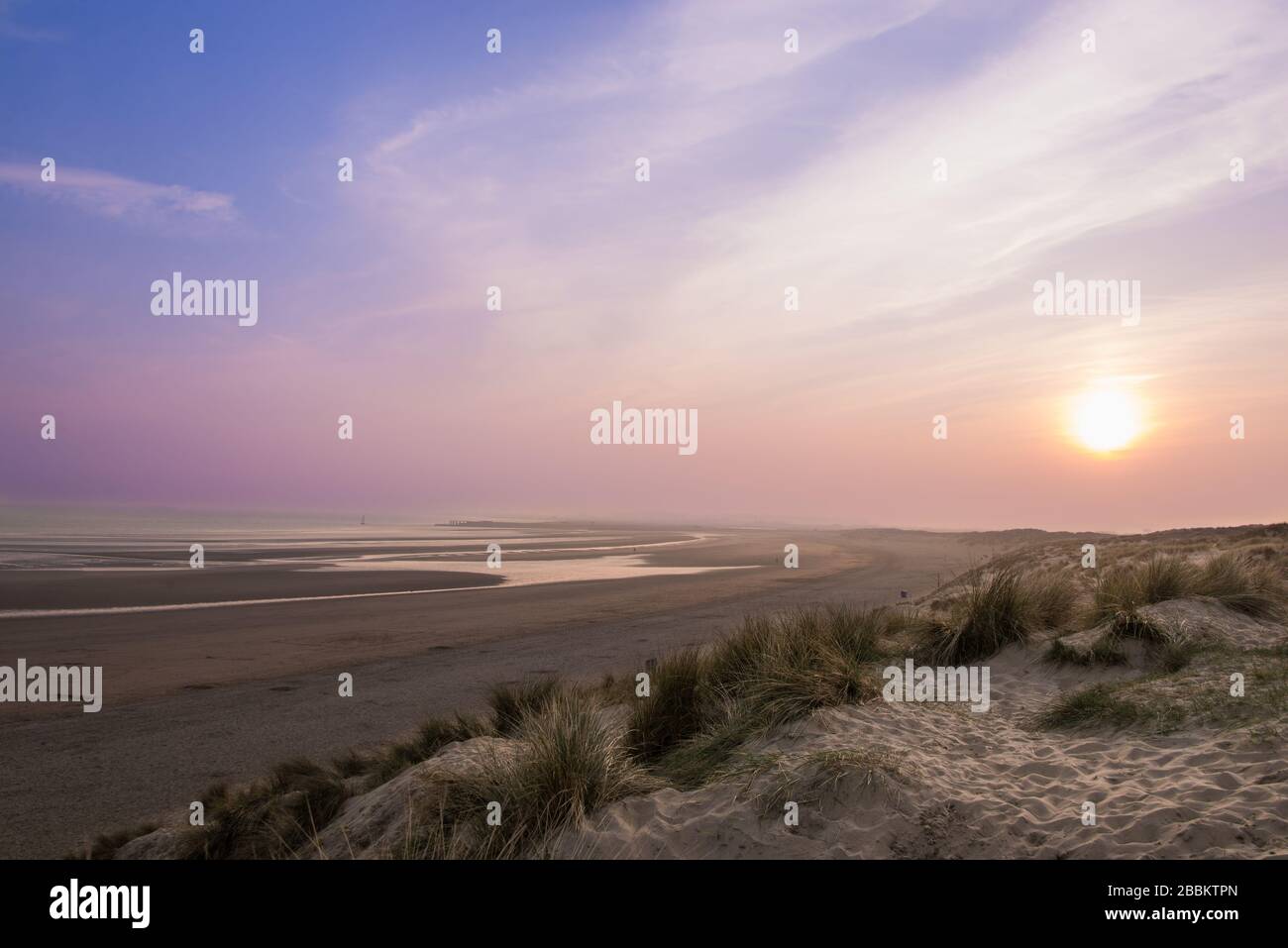 Magnifique coucher de soleil à Camber Sands avec ciel rose et violet. Sable de carrossage, Angleterre, Royaume-Uni Banque D'Images