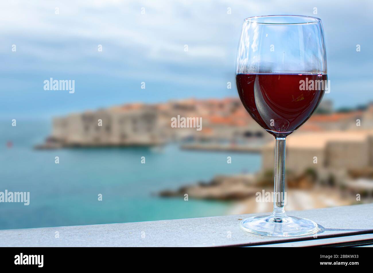 Verre de vin sur la forteresse de Dubrovnik flou arrière-plan. Vue ensoleillée sur un verre de vin rouge surplombant la plage de Dubrovnik, Croatie Banque D'Images