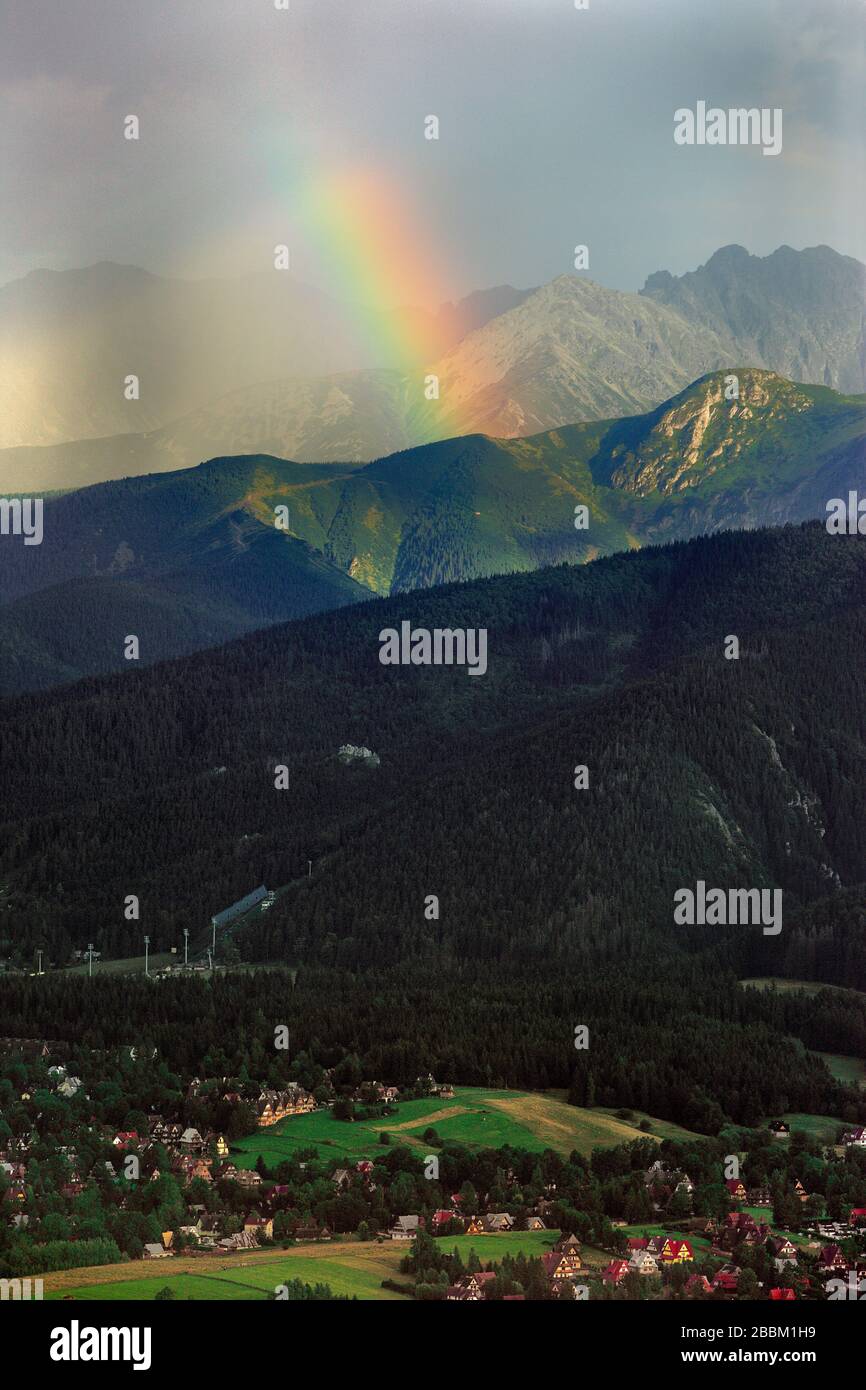 Vue panoramique sur les montagnes des Hautes Tatras avec les pics Kasprowy Wierch, Czerwone Wierchy et Swinica sous un arc-en-ciel vu de Zakopane en Pologne Banque D'Images