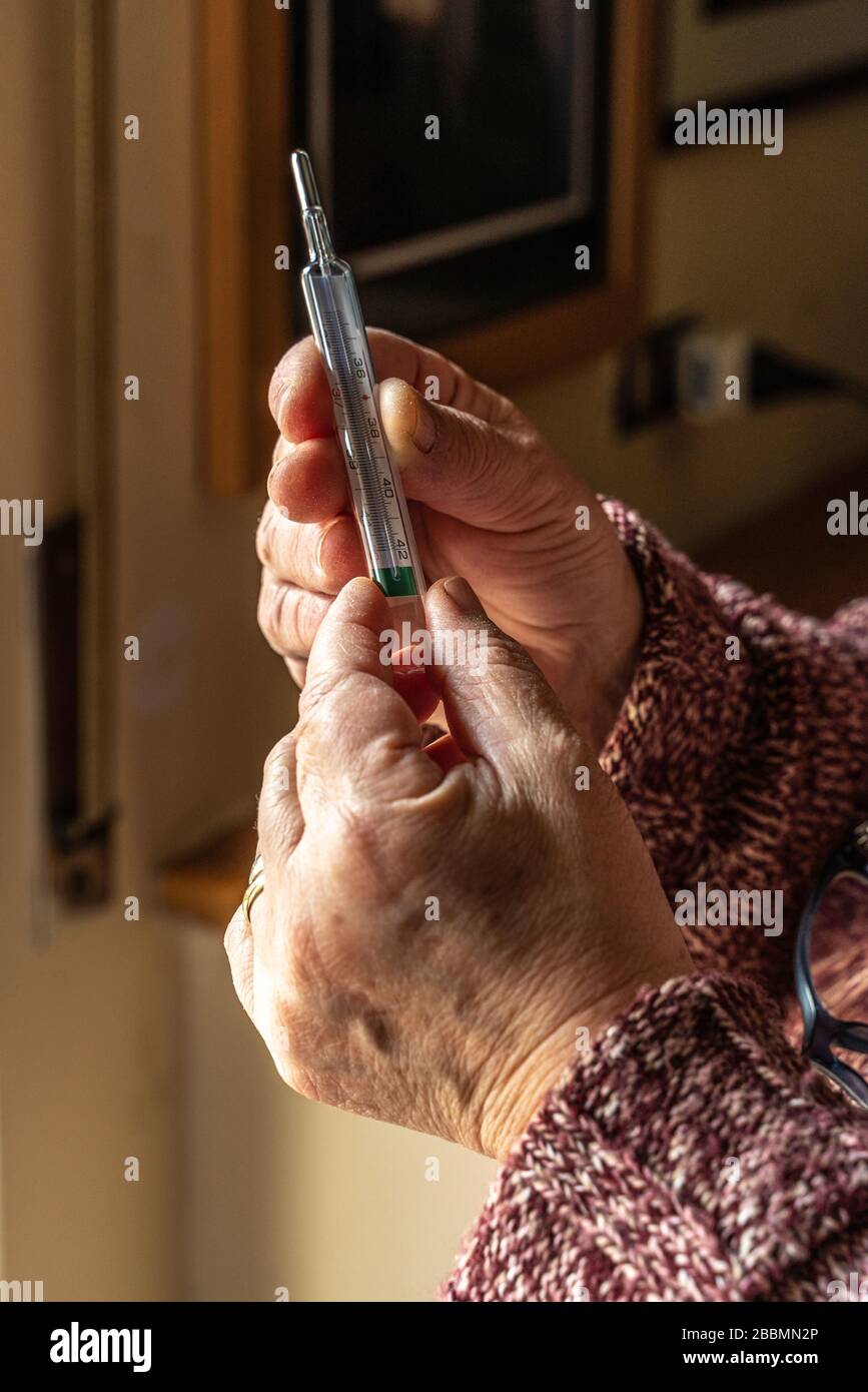 les mains de la femme âgée vérifient la température corporelle Banque D'Images