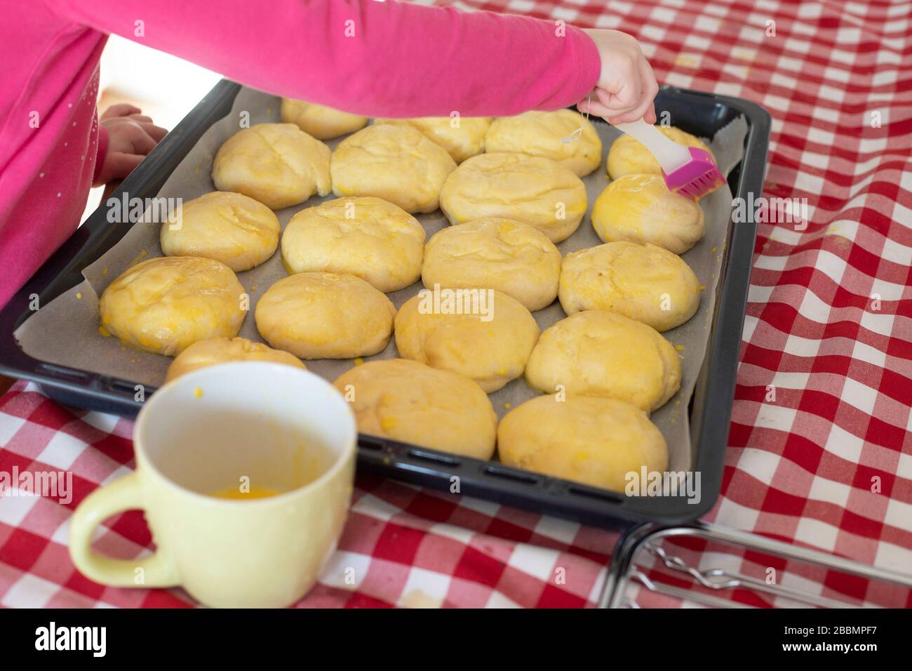 Enfant fille vitrage main pain pains avec lavage d'oeuf avant la cuisson. Idée d'activité de verrouillage. Banque D'Images