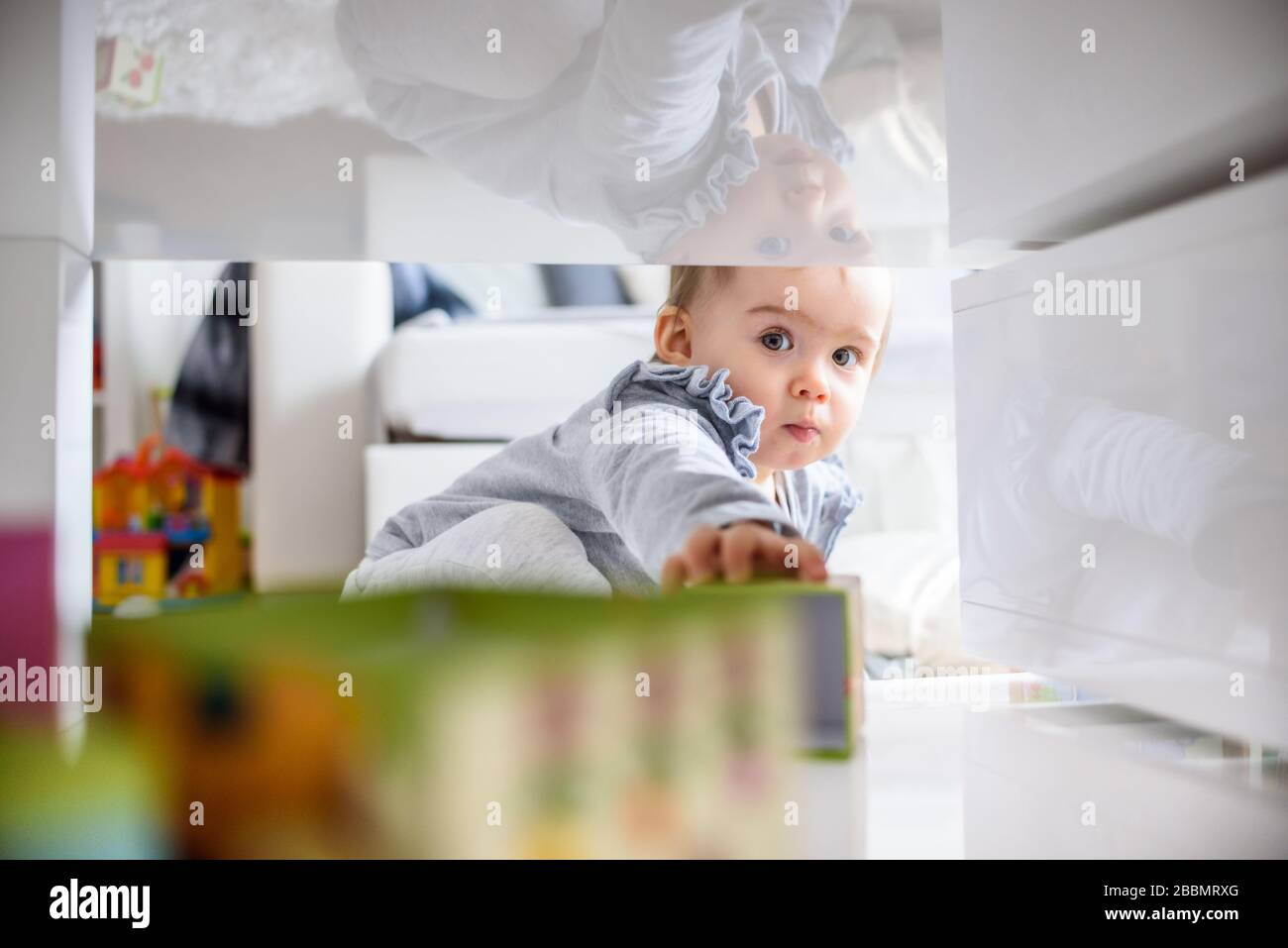 Bébé doux se pressant dans l'espace serré pour obtenir ce qu'elle veut. Banque D'Images