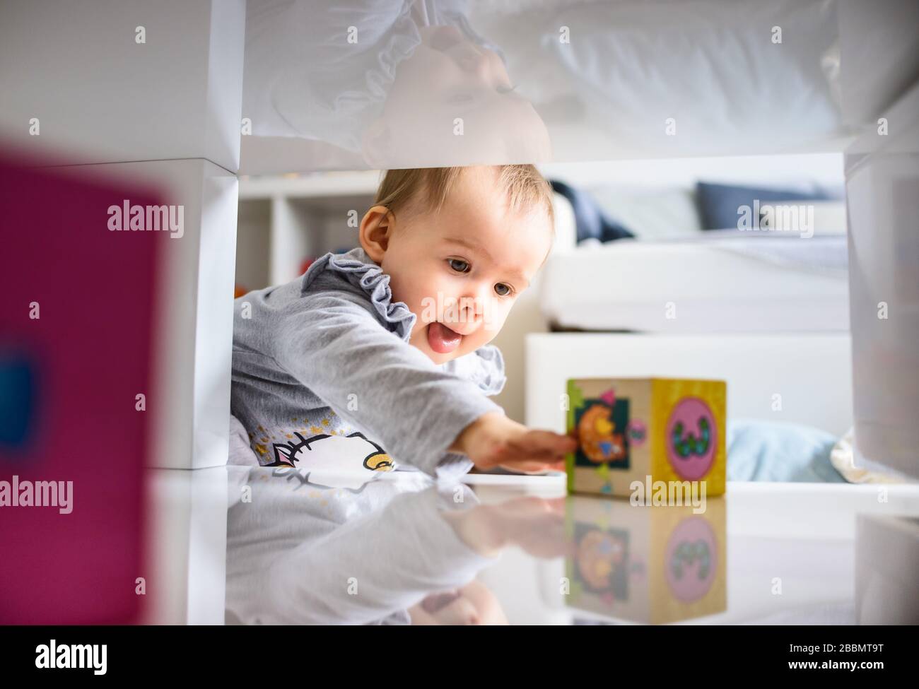 Bébé doux se pressant dans l'espace serré pour obtenir ce qu'elle veut. Banque D'Images