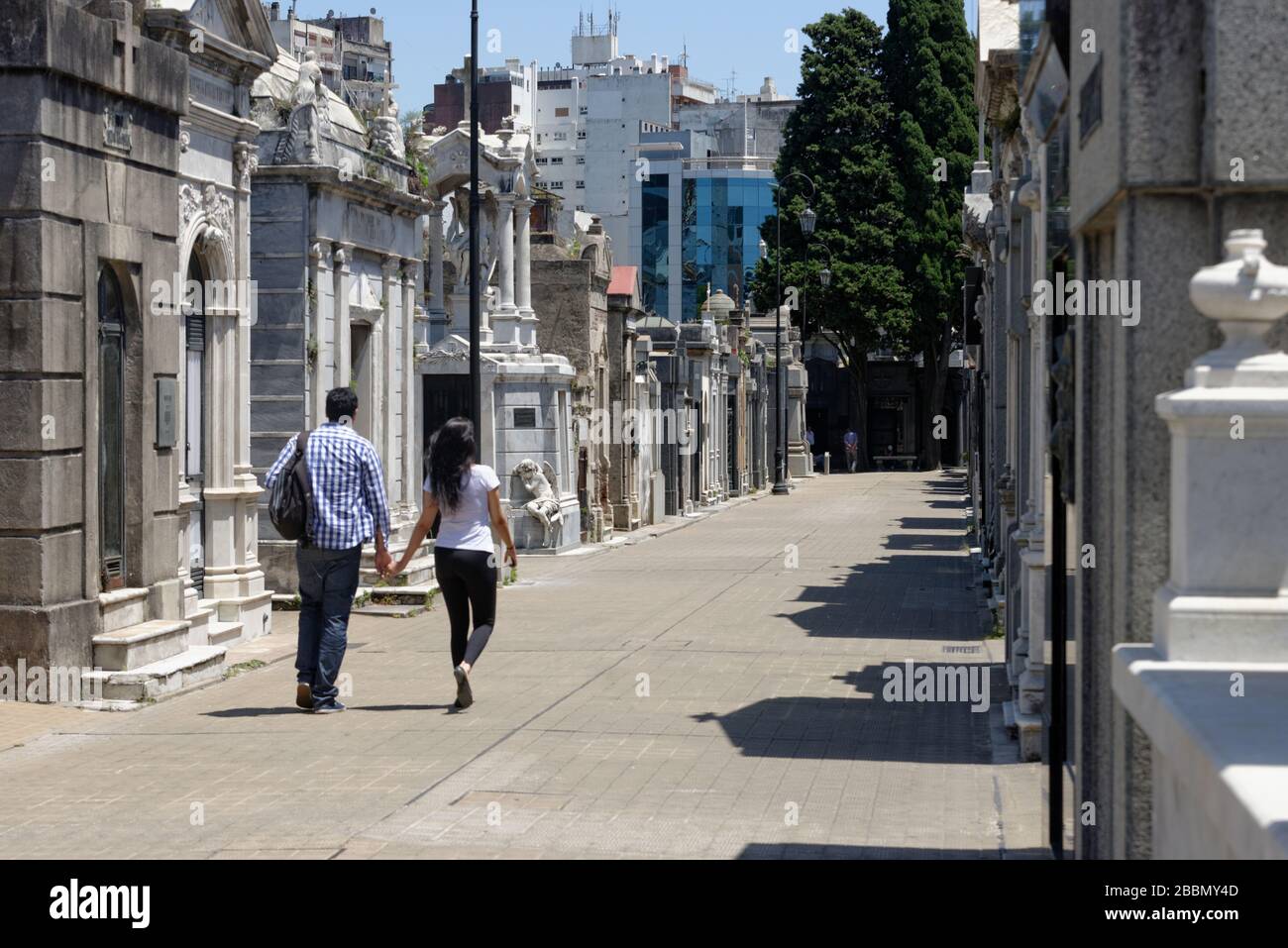 Homme et femme se tenant les mains en marchant dans les tombes bordant les rues étroites du cimetière de la Recoleta dans le centre de Buenos Aires Banque D'Images