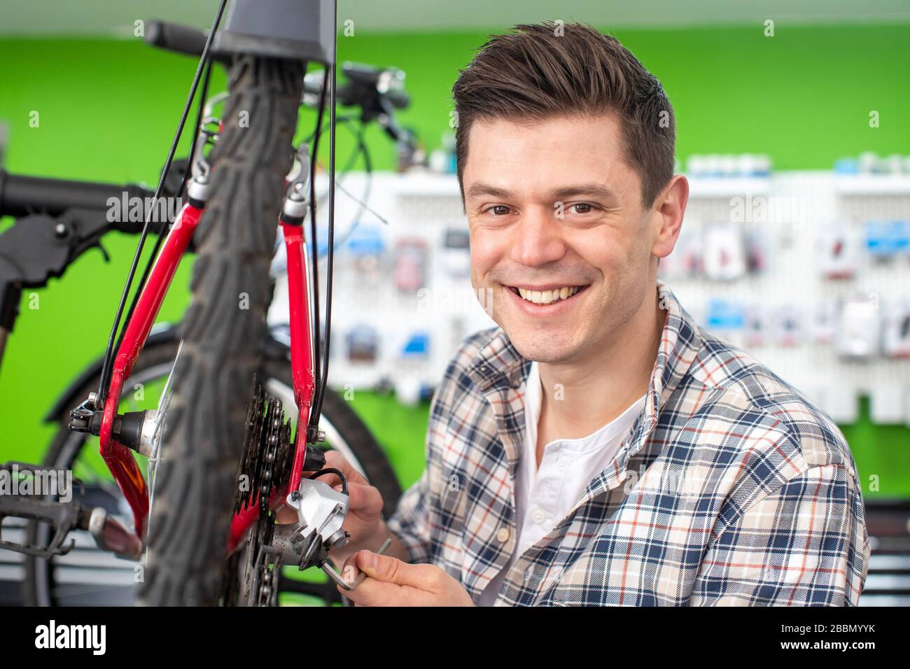 Portrait du propriétaire masculin de la petite entreprise, réparation d'engrenages dans la boutique de réparation de vélos Banque D'Images