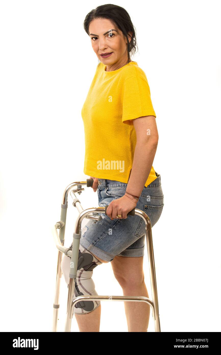 Femme souriante avec cadre de marche et orthèses de jambe isolées sur fond blanc Banque D'Images