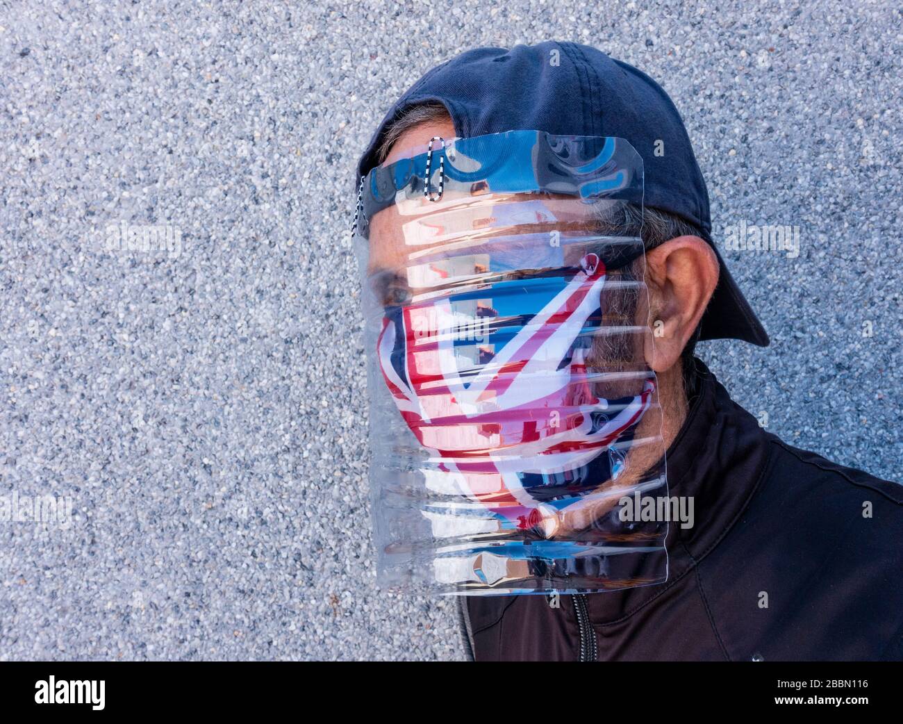 Un homme porte une visière improvisée faite d'une bouteille d'eau avec un masque de visage de cric-raccord sur la bouche et le nez. Coronavirus, Royaume-Uni Banque D'Images