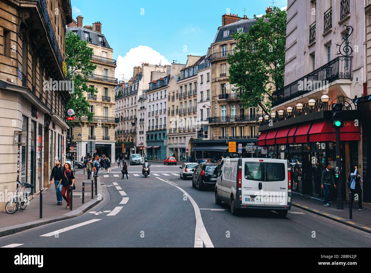 Les gens marchant dans la rue parmi les bâtiments parisiens typiques du centre de Paris, France. Banque D'Images