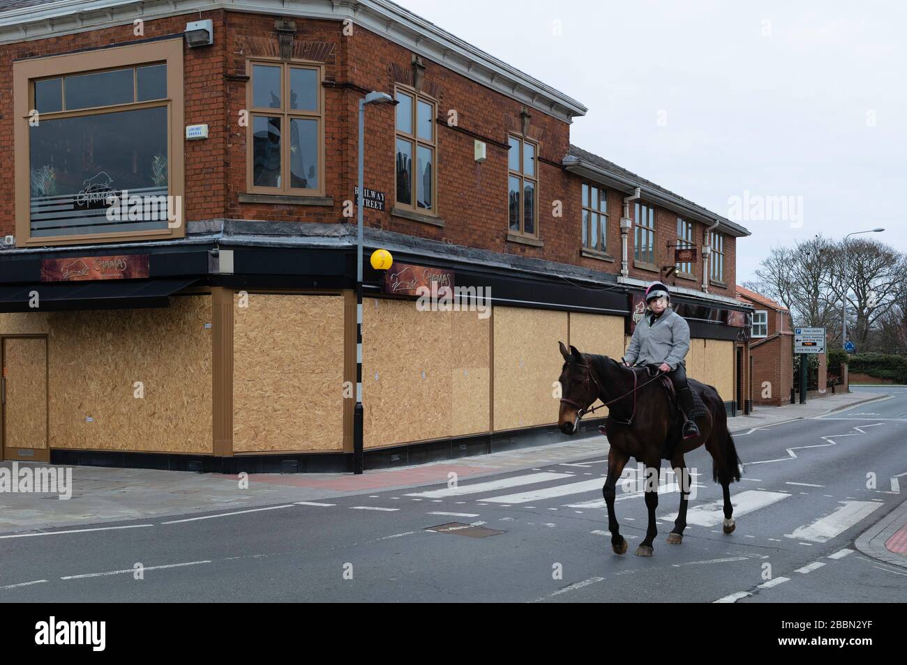 Cavalier seul et cheval sur route flanqué de compagnies embarquées et fermées pendant l'épidémie de virus de Corona à Beverley, Yorkshire, Royaume-Uni. Banque D'Images