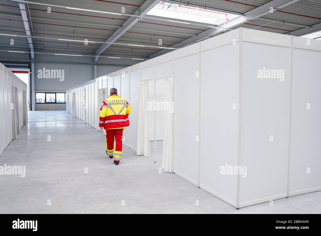 01 avril 2020, Rhénanie-Palatinat, Wörth: Un médecin d'urgence passe devant une aile avec des faucilles dans la station d'aide de Corona. L'hôpital d'urgence est en cours de configuration dans un entrepôt. Photo: Uwe Anspach/dpa Banque D'Images